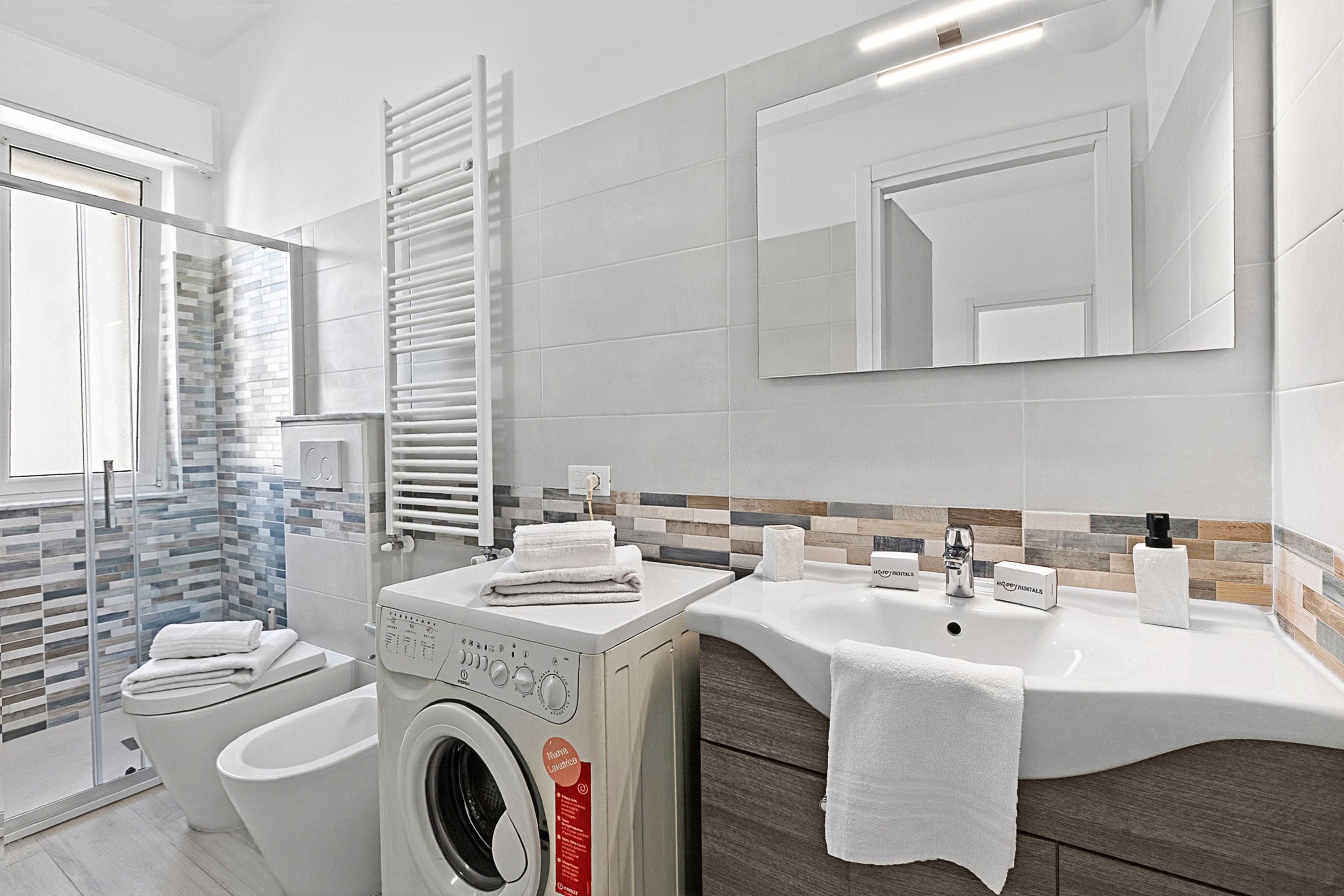 Un bagno moderno con lavatrice, WC e lavandino.