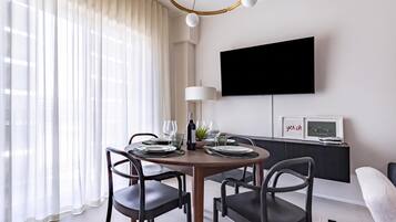 Un comedor moderno con una mesa redonda, sillas y un televisor colocado en la pared.