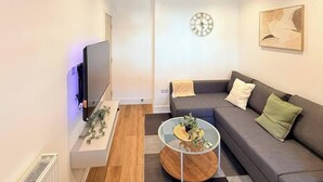 Een moderne woonkamer met een flatscreen televisie, een bank, een salontafel en een wandklok.