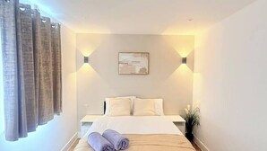 Een hotelkamer met een bed, gordijnen, een wandlamp en een schilderij.