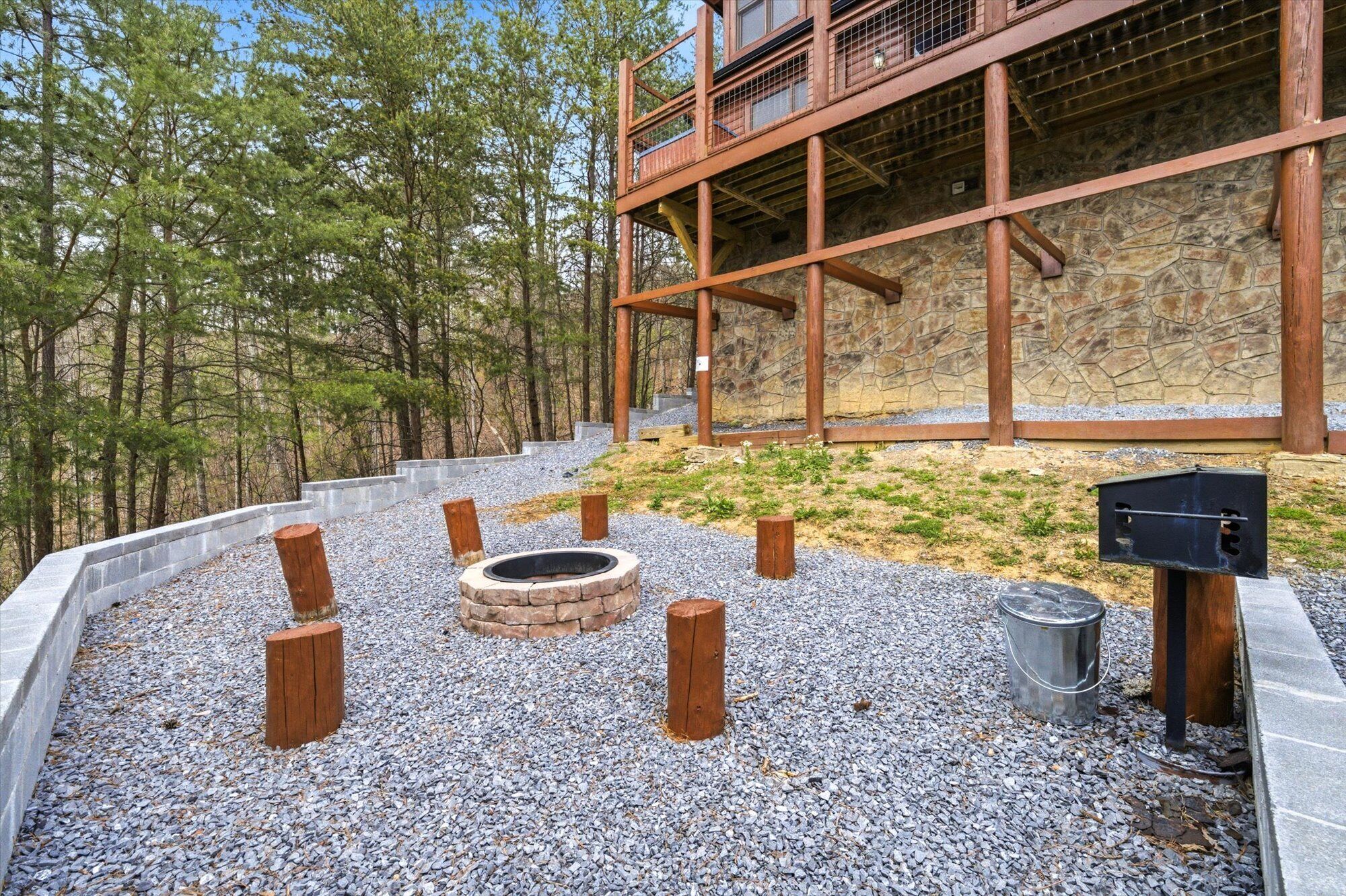 A stone building with a wooden deck and a fire pit area surrounded by gravel.