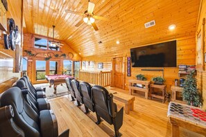A wooden cabin interior with a pool table, seating, a television, and a view of the outdoors. - Red, White and The View (Sevierville)