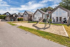 Zona residencial con varias casas, un parque infantil y una calle pavimentada.