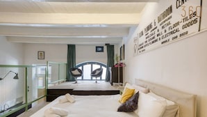 Ein Hotelzimmer mit einem Bett, zwei Stühlen, einem kleinen Tisch und Blick auf einen Balkon.