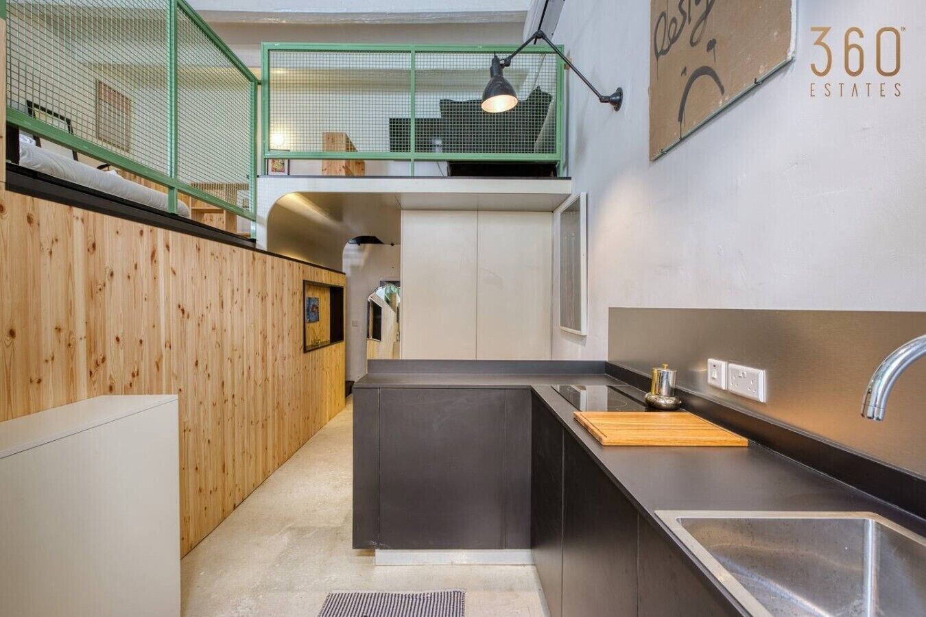 Een moderne keuken met een zwart aanrecht, een roestvrijstalen spoelbak en een houten snijplank.