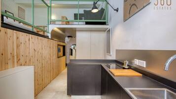 Een moderne keuken met een zwart aanrecht, een roestvrijstalen spoelbak en een houten snijplank.