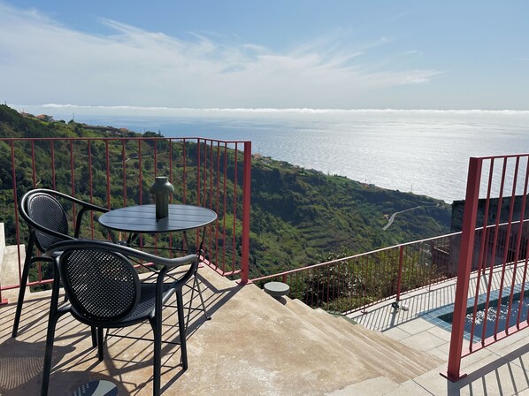 Ein Balkon mit Tisch und Stühlen mit Blick auf eine Küstenlandschaft.