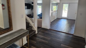 A spacious living area with a staircase leading to an upper level, a dining area, and a view of the outdoors through a glass door. - The Hideout, a spacious 5BR, 3BT home that's perfect for families friends. (Lanham)
