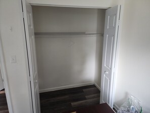 A closet with a metal shelf, a wooden floor, and a white door.