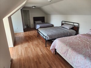 A bedroom with two beds, wooden flooring, and a sloped ceiling. - The Hideout, a spacious 5BR, 3BT home that's perfect for families friends. (Lanham)