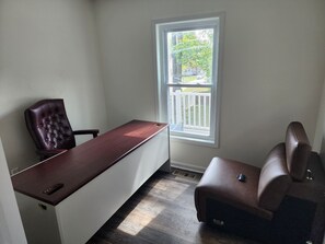 Ein Zimmer mit Schreibtisch, Stuhl und gepolstertem Sitzbrett.