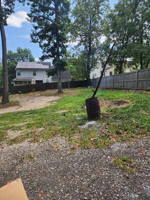A backyard with a gravel path, a wooden fence, and a tree.