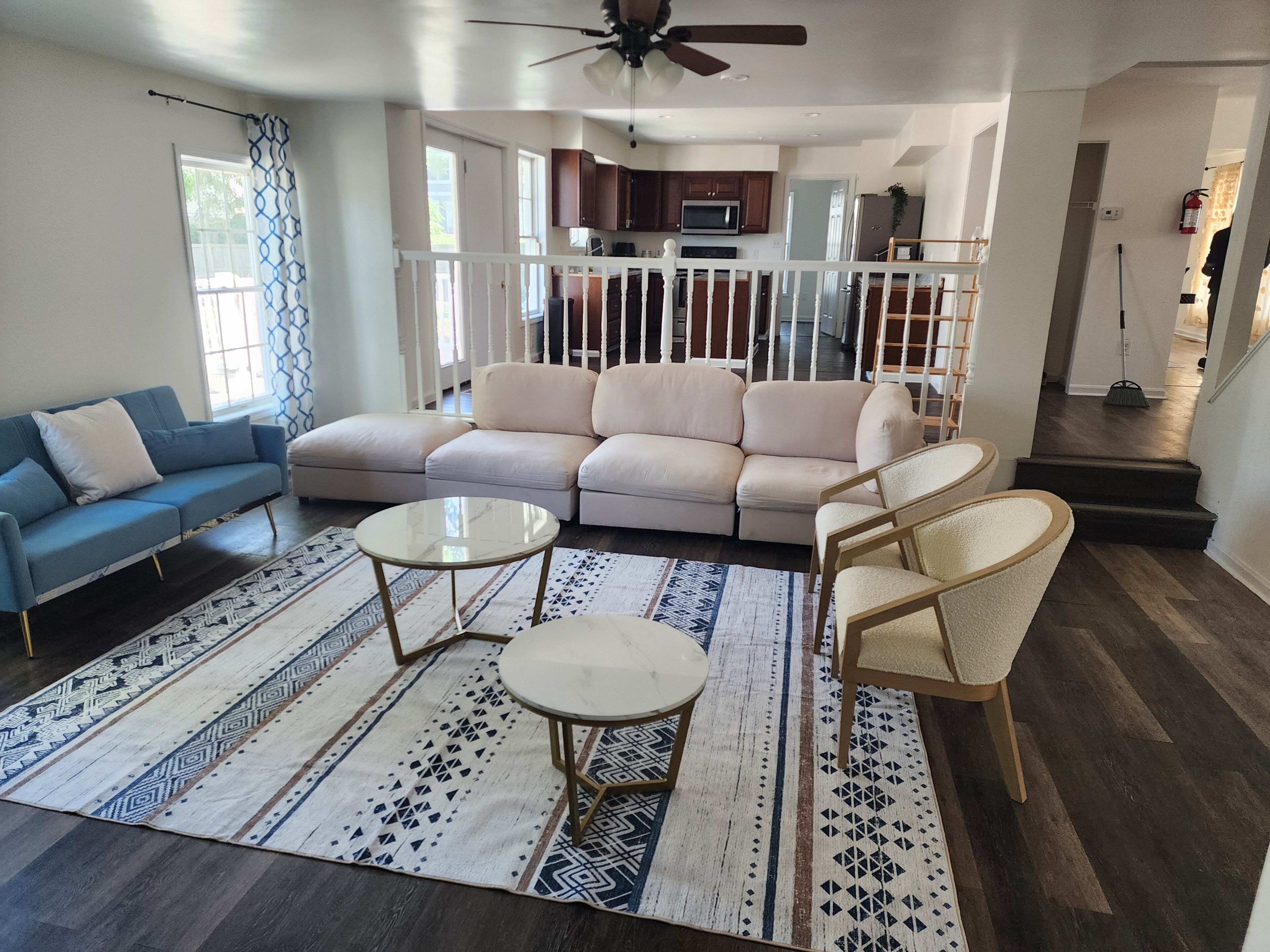 A spacious living room with a large beige sectional sofa, two round coffee tables, and a blue sofa.