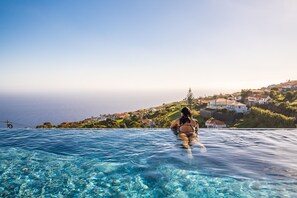 Eine Person in einem Pool mit Blick auf Häuser und ein Gewässer.