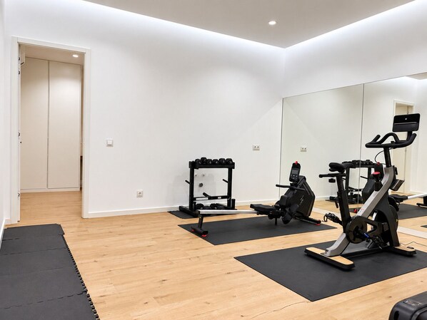 Ein modernes Fitnessstudio mit Trainingsgeräten, Holzböden und einem großen Spiegel.
