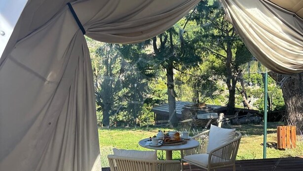 Une tente avec une table et des chaises installées sur une terrasse en bois.