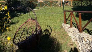 Une chaise, un mur de pierre et une vue sur un paysage montagneux.