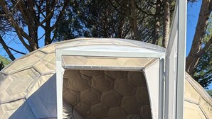 Une tente en forme de dôme, équipée d’un lit, d’un petit bureau et d’un télescope.
