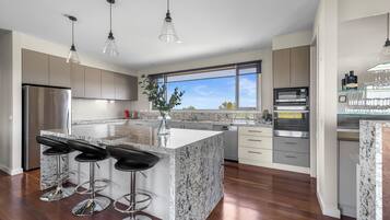 Una cocina moderna con una isla grande, electrodomésticos de acero inoxidable y vistas al exterior.