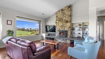 A modern living room with a stone fireplace, leather sofa, and a television.