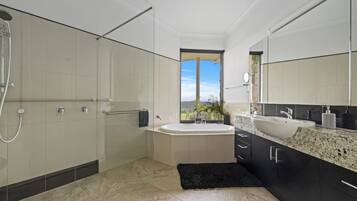 Un bagno moderno con una vasca da bagno ampia, una zona doccia separata e un mobile lavabo con lavandino e specchio.