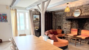 Un coin repas avec une table et des chaises en bois, un mur en pierre et un canapé avec des coussins.