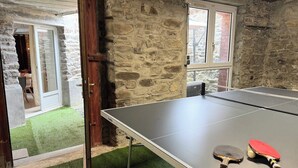 Une table de ping-pong avec deux raquettes, un filet et un mur en pierre.