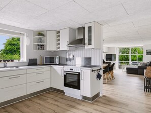 Eine moderne Küche mit weißen Schränken, einem eingebauten Backofen und einer Mikrowelle.