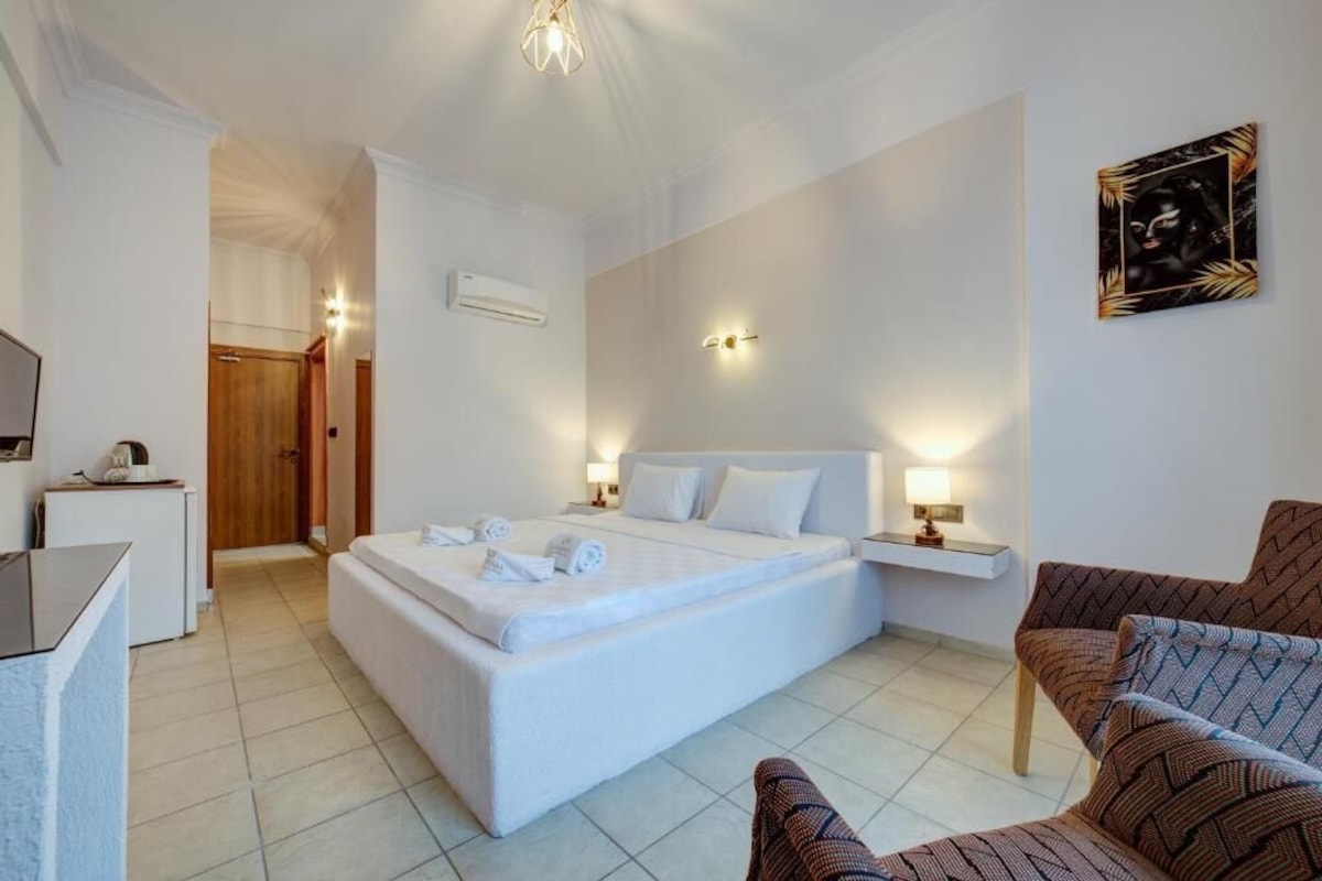 Una habitación de hotel con una cama grande, mesitas de noche, un escritorio y una silla.