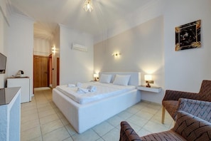 Una habitación de hotel con una cama grande, mesitas de noche, un escritorio y una silla.