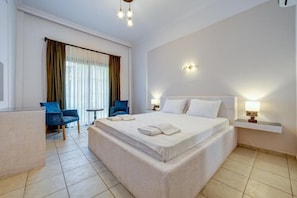 Una habitación de hotel con una cama grande, un escritorio, una silla y un ventanal con cortinas.