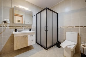 Un baño con tocador, inodoro, cabina de ducha y espejo.
