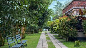 Un sentier qui traverse un jardin agrémenté de bancs et d’une végétation luxuriante.