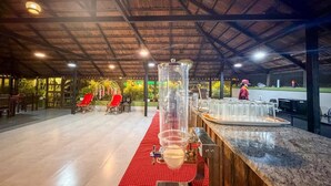 Un espace bar doté d’un grand distributeur cylindrique, d’une nappe à carreaux rouges et d’un comptoir avec des verres.