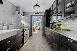 Una cocina moderna con armarios oscuros, encimeras blancas y una isla central.