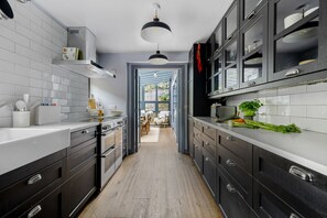 Eine moderne Küche mit dunklen Schränken, weißen Arbeitsplatten und Blick in einen Essbereich.