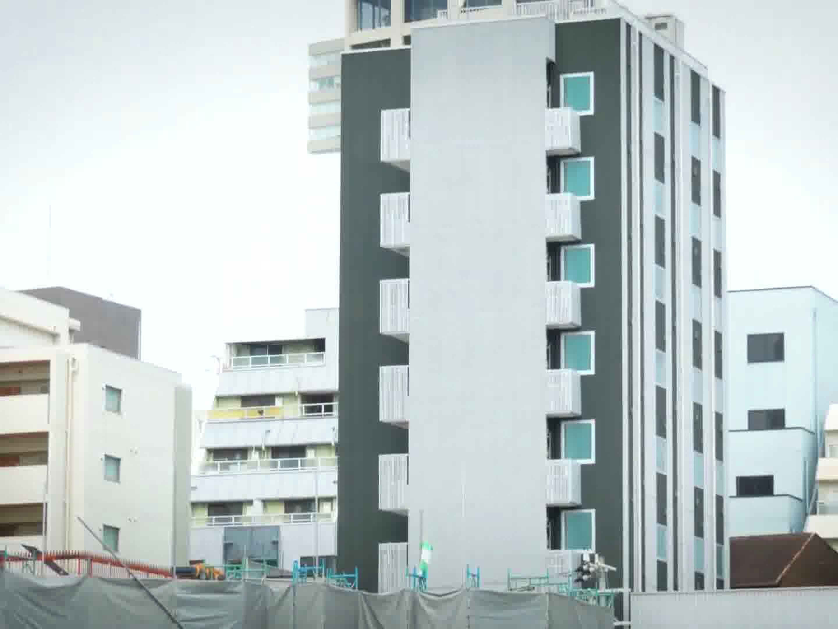 A multi-story building with a modern design, featuring balconies and a flat facade.