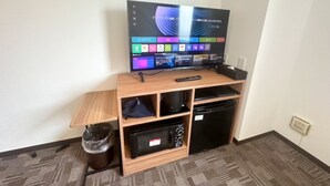 A room with a wooden entertainment unit, a television, and a small black appliance. - HOTEL LiVEMAX Namba WEST (Osaka)