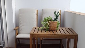 A wooden table and chairs on a tiled patio with a potted plant. - Apartment in Conil, located in one of the best areas (Conil de la Frontera)