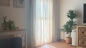 A living room with a sofa, a dining table, a potted plant, and a chandelier. - Apartment in Conil, located in one of the best areas (Conil de la Frontera)