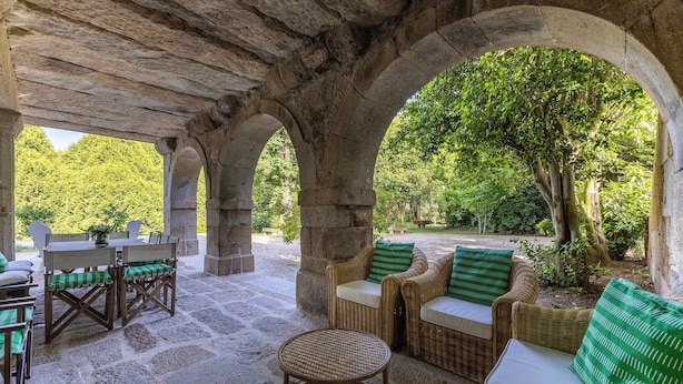 A stone-arched outdoor seating area with wicker furniture and a round table. - Carcavelos Manor House by Portugal Active (Vila Verde)