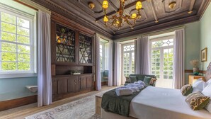 A bedroom with a large bed, wooden cabinets, and a chandelier. - Carcavelos Manor House by Portugal Active (Vila Verde)