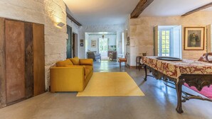 A room with a sofa, a table with a patterned tablecloth, a wooden bench, and a painting on the wall. - Carcavelos Manor House by Portugal Active (Vila Verde)