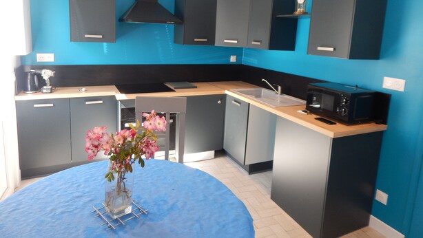 A modern kitchen with blue walls, black cabinets, and a wooden countertop. - Saint-Malo: Beautiful apartment, 300 m from the train station and Sillon Beach, within the city walls (Saint-Malo)
