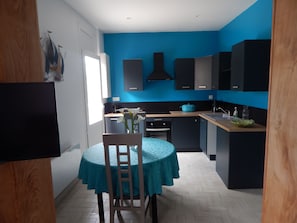 Eine moderne Küche mit blauen Wänden, einem Esstisch mit einem blaugrünen Tischläufer und einem Stuhl.
