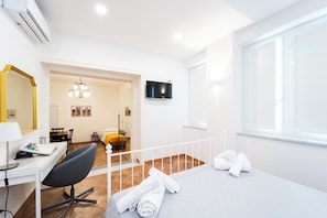 A hotel room with a bed, a desk with a chair, a TV, and a window. - Maison Nunzia (Naples)