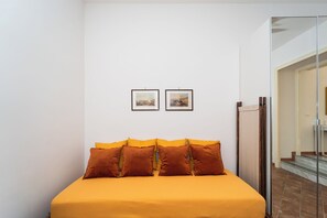 Ein Schlafzimmer mit einem Bett, zwei gerahmten Bildern an der Wand und einem Spiegel.