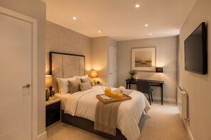 Ein modernes Hotelzimmer mit Bett, Nachttischen, einem Schreibtisch und einem Fernseher.
