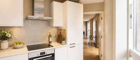 Una cocina moderna con armarios blancos, un horno Bosch y una botella de vino en la encimera.