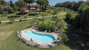 A swimming pool with lounge chairs and umbrellas, surrounded by a stone deck. - Siena Holiday Home With Pool for 4 (Siena)